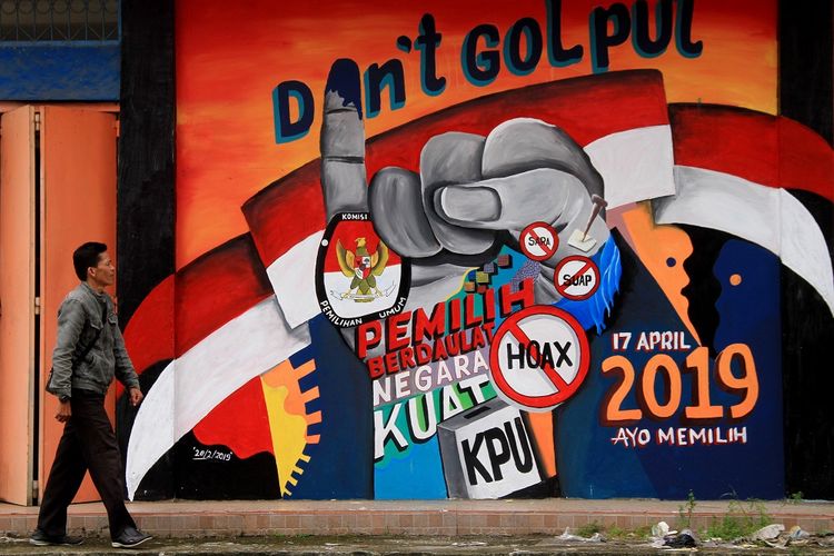 Warga melintas di depan mural tentang pemilu 2019 di Pasar baru Mamuju, Sulawesi Barat, Rabu (6/03/2019). Mural tersebut mengangkat tema mengajak warga untuk mensukseskan pemilu pada 17 April 2019 dengan berpartisipasi dan tidak Golput. ANTARA FOTO/ Akbar Tado/hp.