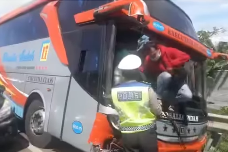 Tangkapan layar video yang memperlihatkan seorang anggota polisi lalu lintas (polantas) sedang membantu proses evakuasi penumpang saat bus yang ditumpangi mengalami kecelakaan.