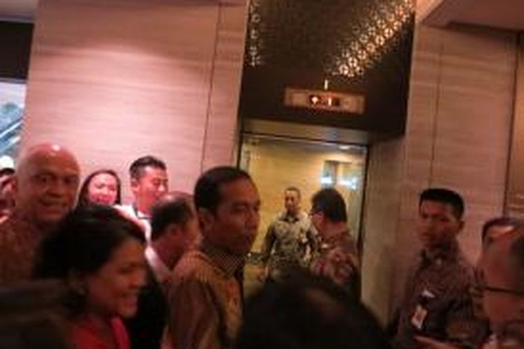 Dikerubungi warga yang berebutan ingin mendekatinya, Presiden Joko Widodo dan Ibu Iriana Widodo berjalan bergerak ke lift Hotel Mandarin Orchard