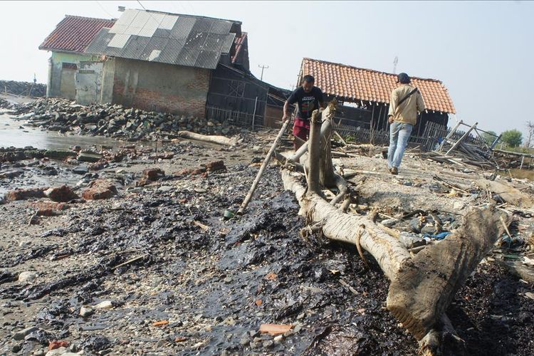 Seorang warga menunjukkan ceceran tumpahan minyak di pantai Desa Cemarajaya, Kecamatan Cibuaya, Kabupaten Karawang, Senin (22/7/2019).