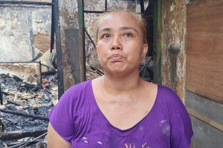 Ibu tujuh anak, Amalia (42) memungut panci dan wajan yang bisa diselamatkan di Jalan Cikini Kramat, Pegangsaan, Menteng, Jakarta Pusat pada Selasa (27/9/2022). 
