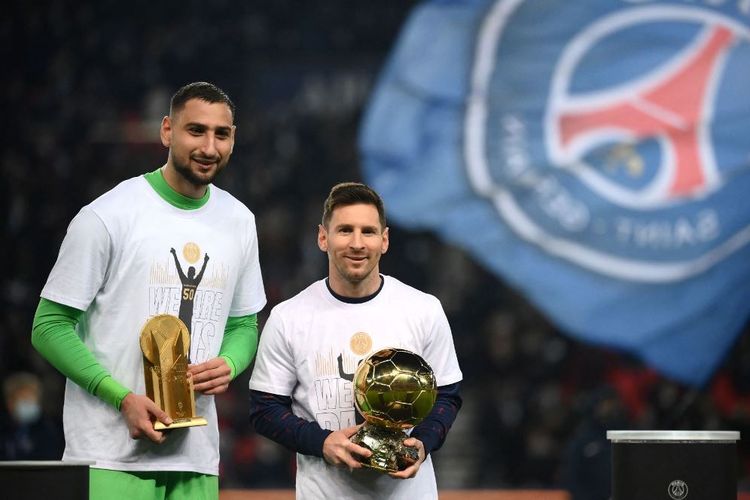 Penyerang Paris Saint-Germain, Lionel Messi (kanan), menggenggam trofi Ballon d'Or 2021. Dia berdiri bersama rekan setimnya, Gianluigi Donnarumma, yang merupakan penjaga gawang. Donnarumma menyabet penghargaan Yashin Trophy untuk penjaga gawang terbaik.