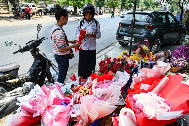 Seorang siswa (kanan) membeli bunga pada Hari Valentine di Phnom Penh pada tanggal 14 Februari 2024. Pihak berwenang di Kamboja telah mengeluarkan teguran keras kepada para siswa untuk menghindari kegiatan yang tidak pantas pada Hari Valentine ini, dan memperingatkan mereka akan bahaya kehilangan martabat. 
