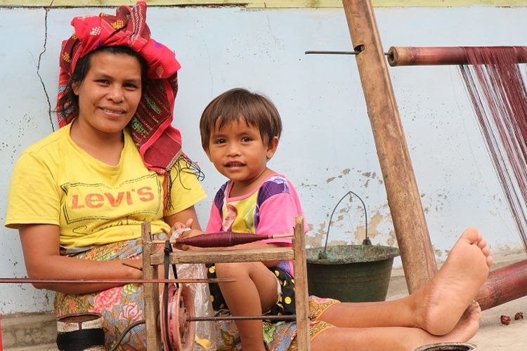 Ibu dan anak sedang beristirahal dama membuat ulos.