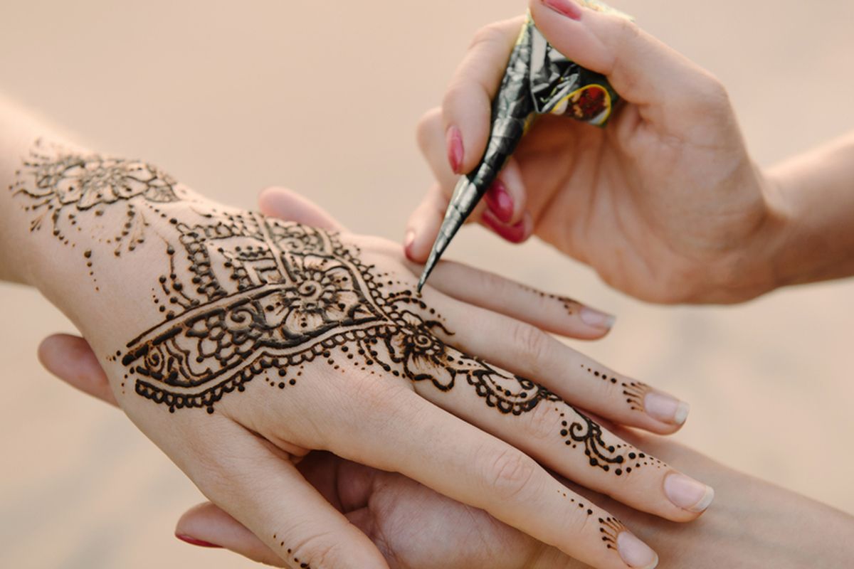 Artis menerapkan tato henna di tangan wanita. Mehndi adalah seni dekoratif tradisional India. Close-up