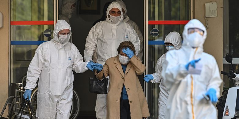 Petugas medis mengenakan pakaian pelindung (hazmat) mengawal perempuan yang diduga terinfeksi virus corona di Istanbul, Turki, pada 12 April 2020.