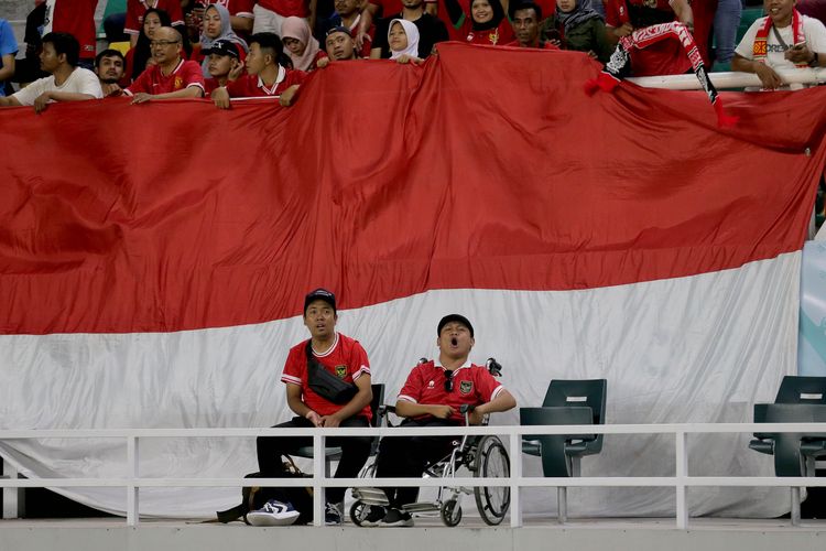 Wiviano seorang suporter disabilitas Timnas Indonesia (kanan) ditemani temannya saat menyaksikan babak penyisihan Grup A Piala Dunia U17 2023 Indonesia melawan Ekuador yang berakhir dengan skor 1-1 di Stadion Gelora Bung Tomo Surabaya, Jawa Timur, Jumat (10/11/2023) malam.