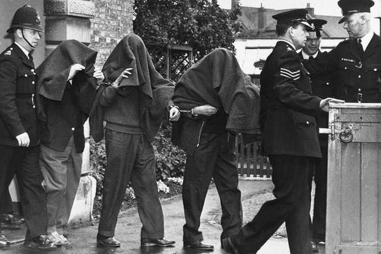 Tiga dari tersangka ditangkap sehubungan dengan Perampokan Kereta Api Besar meninggalkan pengadilan dengan selimut menutupi kepala mereka, 1963.
