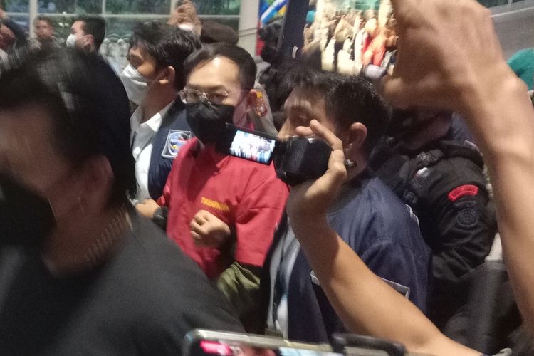 Tersangka kasus dugaan judi online di Kompleks Cemara Asri, Deli Serdang, Apin BK mengenakan kemeja tahanan dan tangan diborgol saat tiba di Bandara Internasional Kualanamu pada Senin (17/10/2022) sore.