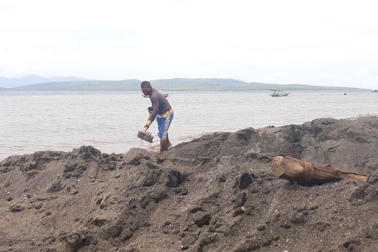 Seorang warga menimbun lubang dengan pasir di pesisir Desa Bangsring, Kecamatan Wongsorejo, Kabupaten Banyuwangi, Jawa Timur yang merupakan kawasan perairan utara Selat Bali, Minggu (4/4/2021).