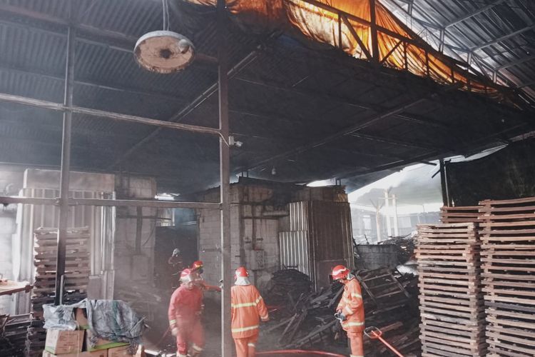 Petugas memadamkan api yang membakar pabrik briket