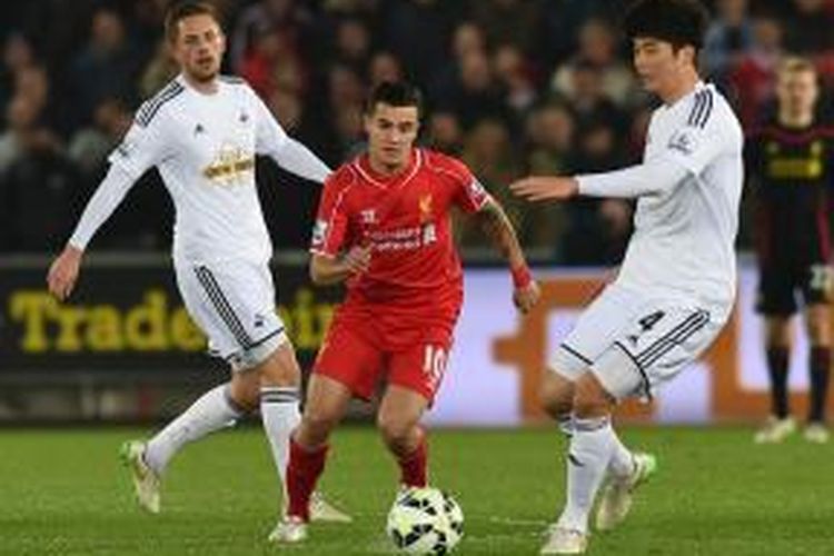 Gelandang Liverpool, Philippe Coutinho, saat berusaha keluar dari kawalan para pemain Swansea City, pada lanjutan Premier League, di Stadion LIberty, Senin (16/3/2015).