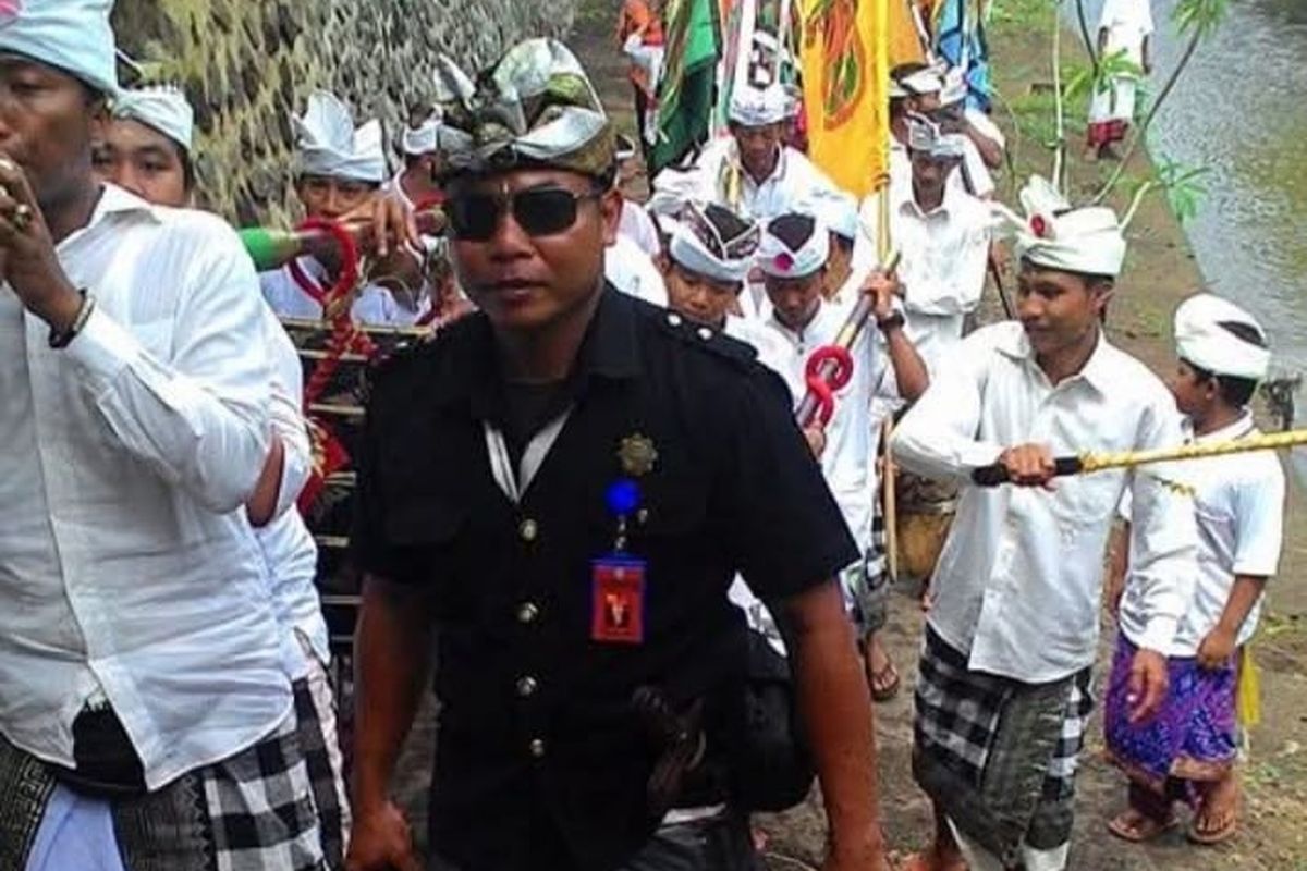 I Ketut Budiarta, seorang pecalang berusia 49 tahun, menjalankan tugasnya dengan penuh dedikasi di Desa Adat Cemenggoan, Kabupaten Gianyar.