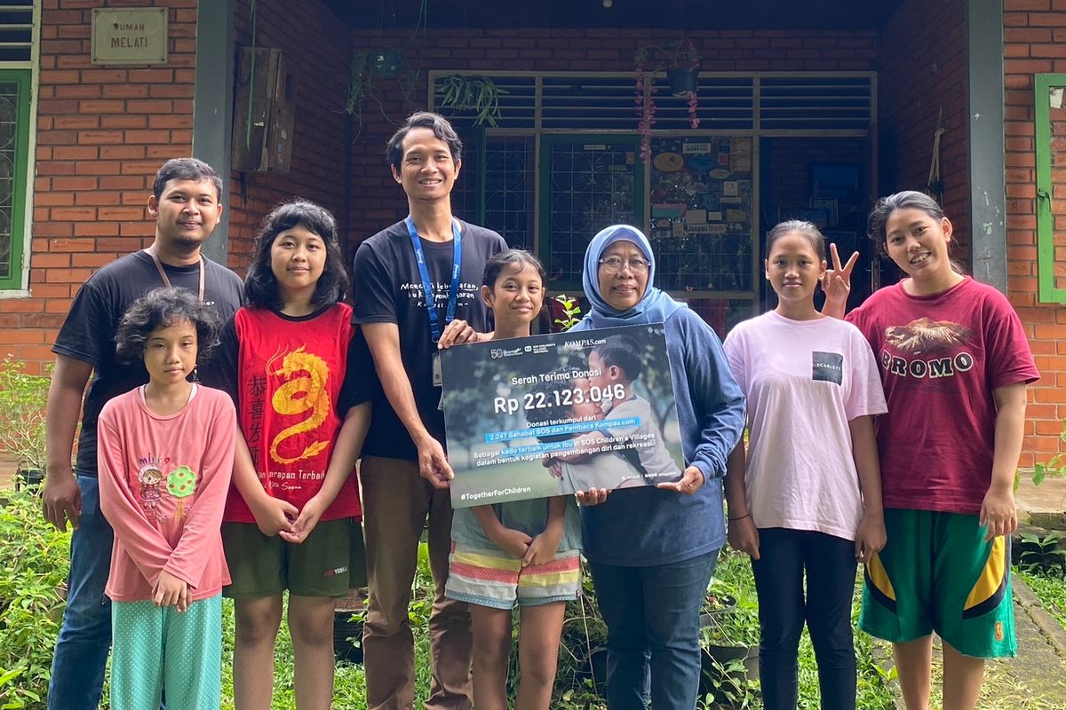 Mohammad Zainal dan Brahmanda Pandya dari Marketing Communication ι.com mewakili ι.com dalam penyerahan simbolis bantuan di salah satu rumah SOS Children?s Villages bersama salah satu ibu pengasuh Maryatun dan anak-anak 