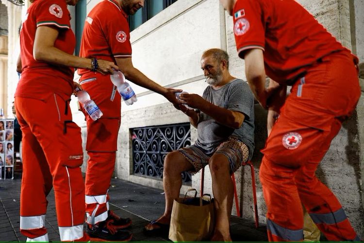  Petugas Palang Merah Italia membantu Antonio seorang gelandangan yang pingsan karena udara panas.(Reuters: Guglielmo Mangiapane)