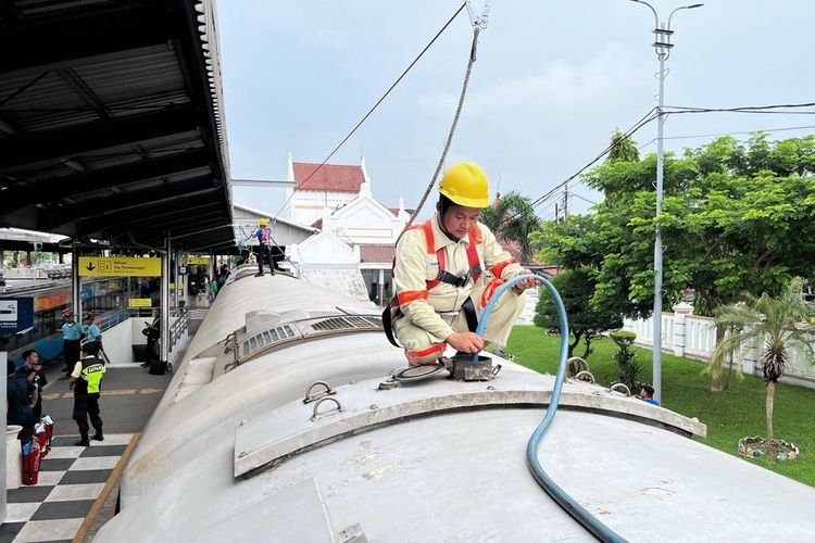 Terlihat petugas KAI sedang mengisi ulang air di tangki toilet di lokasi stabling cuci kereta.