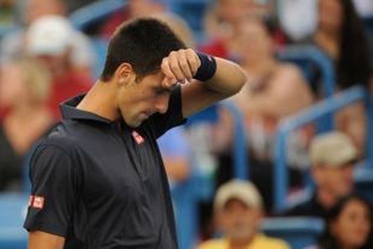 Petenis Serbia, Novak Djokovic mengelap keringat ketika menjalani laga babak kedua Western & Southern Open melawan petenis Perancis, Gilles Simon, di Cincinnati, Selasa (12/8/2014). Djokovic menang 6-3, 4-6, 6-4.