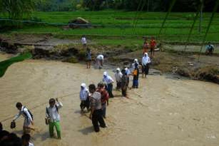 Pelajar menyeberang sungai Cisarua di Desa Bantarkalong, Kecamatan Warungkiara, Sukabumi, Jawa Barat, Senin (28/11/2016). Banjir bandang sungai Cisarua, Minggu (27/11/2016) sore merobohkan jembatan antar kampung yang biasa dimanfaatkan pelajar dan warga lainnya. 