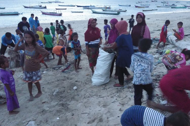 Para istri nelayan dan anak-anak serta petugas dari Balai Konservasi Kawasan Perairan Nasional (BKKPN) Kupang, Nusa Tenggara Timur (NTT), sedang membersihkan sampah di pantai Kelurahan Sulamu, Kabupaten Kupang, Sabtu (21/4/2018)