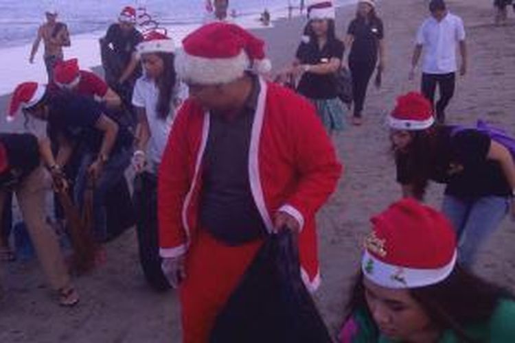 Berpakaian ala Santa Klaus, karyawan Hotel Grand Istana Rama bersih-bersih Pantai Kuta, Bali, Sabtu (20/12/2014).