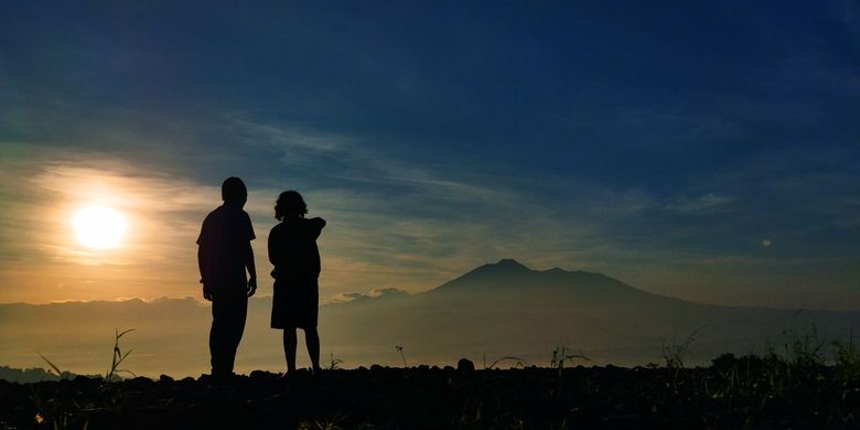 Dua orang wisatawan tengah menikmati pemandangan Gunung Gede Pangrango saat momen golden sunrise yang dilihat dari Desa Pasirjaya, Kecamatan Cigombong, Kabupaten Bogor pada Kamis (27/5/2021).