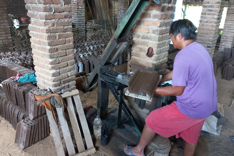 Seorang perajin genting dengan alat cetaknya di sentra produksi genting Desa Manyaran, Kecamatan Banyakan, Kabupaten Kediri, Jawa Timur.