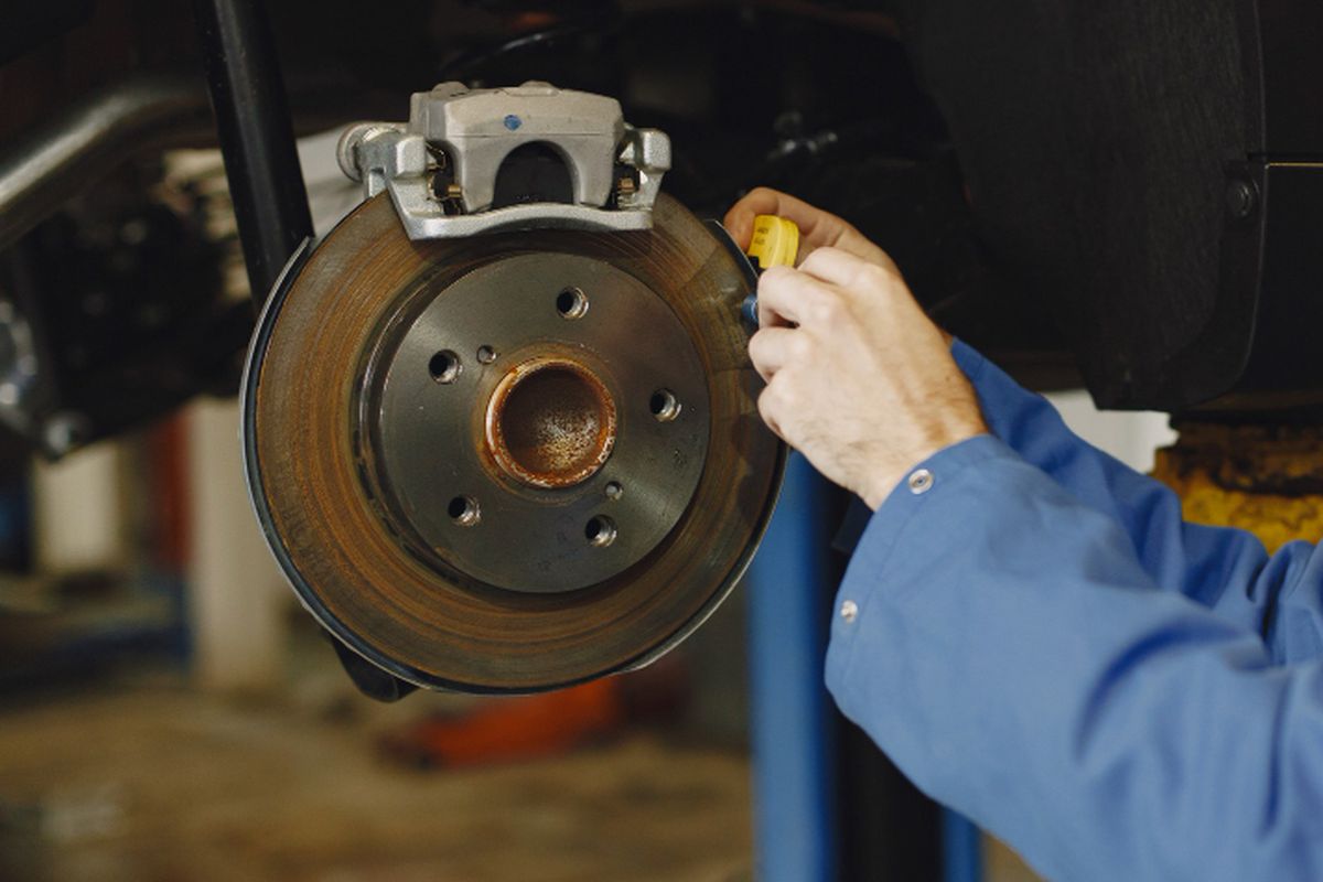 Ilustrasi mekanik memeriksa cakram disk brake yang berkarat
