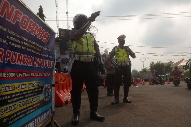 Petugas mengalihkan kendaraan yang hendak menuju Puncak di Bunderan Cepu 8 Cianjur, Jawa Barat, Minggu (16/5/2021), sejurus adanya penutupan jalur Puncak hingga petang nanti.