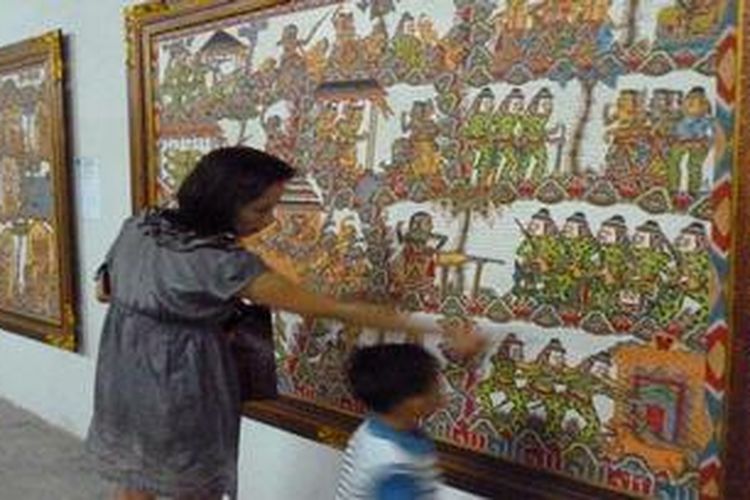 Seorang ibu tengah memperlihatkan lukisan wayang klasik kepada anaknya, di Museum Gunarsa, Kabupaten Klungkung, Bali, Minggu (14/10/2012) malam. Lukisan ini merupakan bagian dari Festival Internasional Pameran Seni Lukis Klasik Bali Perdana yang digelar sejak Juli hingga 28 Oktober mendatang.
