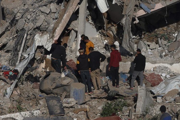 Warga Palestina memandangi puing-puing permukiman yang hancur di Rafah, selatan Jalur Gaza, setelah serangan udara Israel pada Senin (4/12/2023).