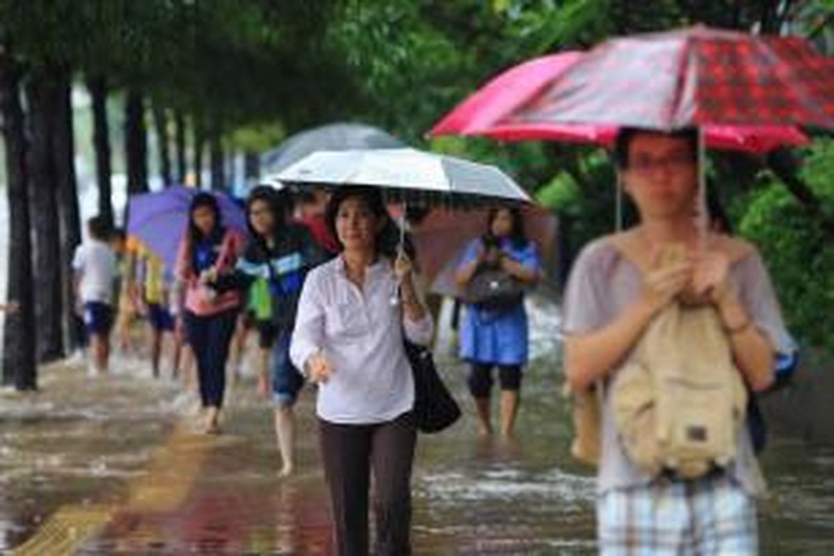 Warga melintas di Jalan MH Thamrin saat hujan mengguyur Jakarta, Senin (9/2/2015). Hujan lebat mengakibatkan sejumlah ruas jalan di Jakarta dan sekitarnya terendam banjir dan menyebabkan kemacetan.