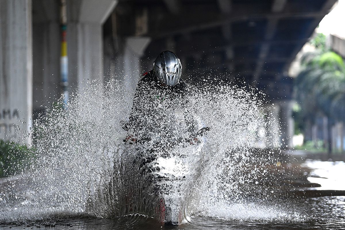 Pengendara sepeda motor mencoba melintasi banjir di Jalan Yos Sudarso, Kelapa Gading, Jakarta Utara, Minggu (23/2/2020). Hujan deras sejak Minggu 23 Februari dini hari membuat sejumlah daerah di Ibu Kota tergenang banjir.