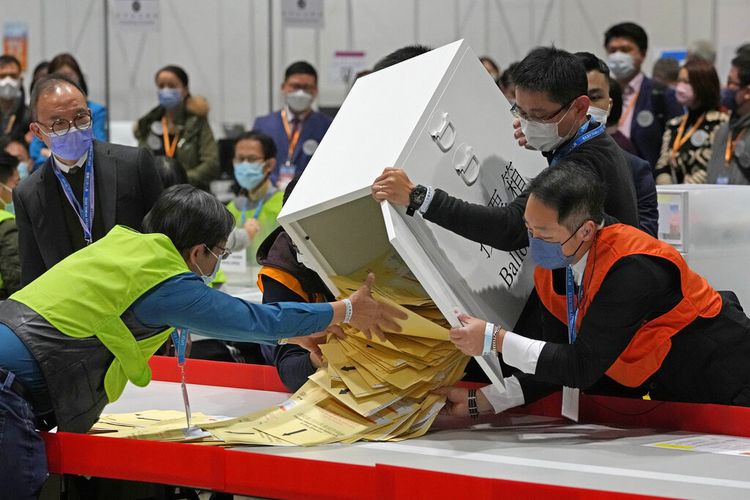 Petugas pemilu mengosongkan kotak suara untuk menghitung suara di tempat pemungutan suara untuk pemilihan legislatif untuk pemilihan legislatif di Hong Kong Minggu, 19 Desember 2021.