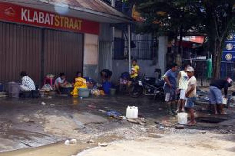 Warga korban banjir mencuci baju di tepi jalan.