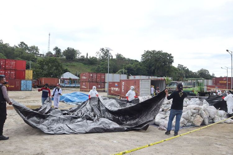 Petugas berwenang dengan menggunakan Alat Pelindung Diri (APD) membuka dan memeriksa isi konteiner yang jatuh di laut Namlea, Senin (3/4/2023)