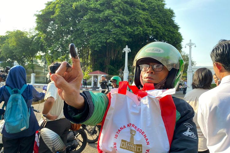 Pengemudi ojek daring (ojek online/ojol) menunjukkan jari bertinta sebagai tanda tanda telah menerima paket sembako yang dibagikan oleh Presiden Joko Widodo di depan Istana Merdeka, Jalan Medan Merdeka Utara, Jakarta Pusat, Senin (8/5/2024). 