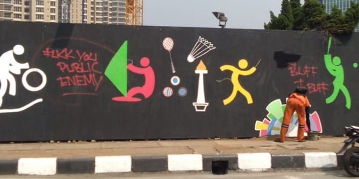Petugas penanganan prasarana dan sarana umum (PPSU) Kelurahan Pondok Pinang membersihkan coretan-coretan yang mengotori mural Asian Games 2018 di perempatan Pondok Indah Mall, Jakarta Selatan, Rabu (25/7/2018).