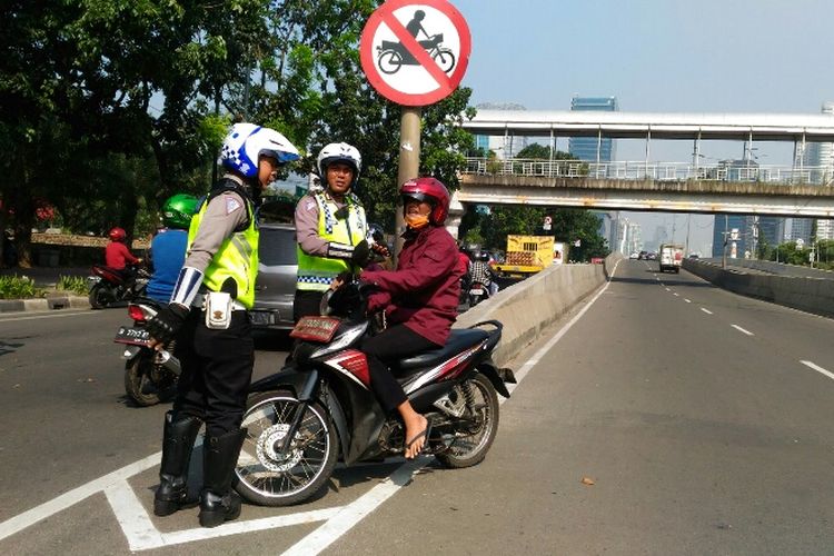 Polisi melakukan penindakan terhadap pengendara motor yang masih nekat melintas di JLNT Casablanca, Selasa (25/7/2017).