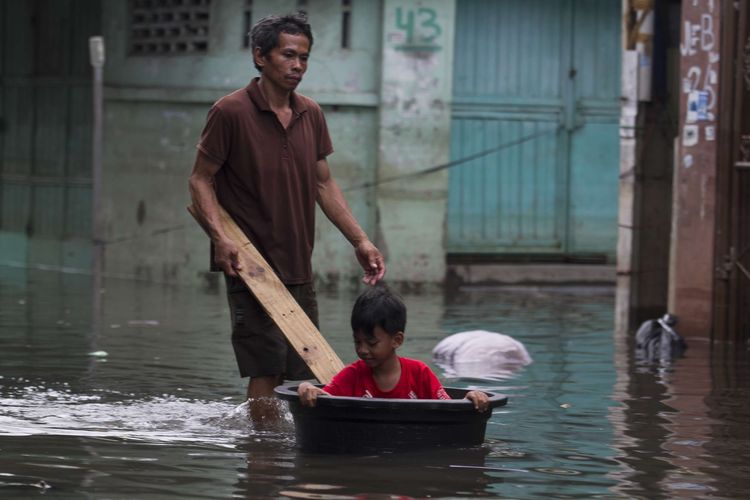 Warga tetap beraktivitas meski rumah mereka terendam banjir di wilayah Teluk Gong, Penjaringan, Jakarta Utara, Sabtu (4/1/2020).Hujan lebat di awal tahun membuat kawasan teluk gong masih terendam banjir.