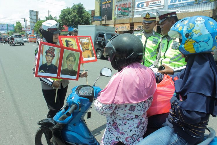 Petugas dari Satlantas Polres Purbalingga menunjukkan gambar wajah pahlawan nasional untuk ditebak oleh para pelanggar dalam operasi zebra, Jumat (10/11/2017).