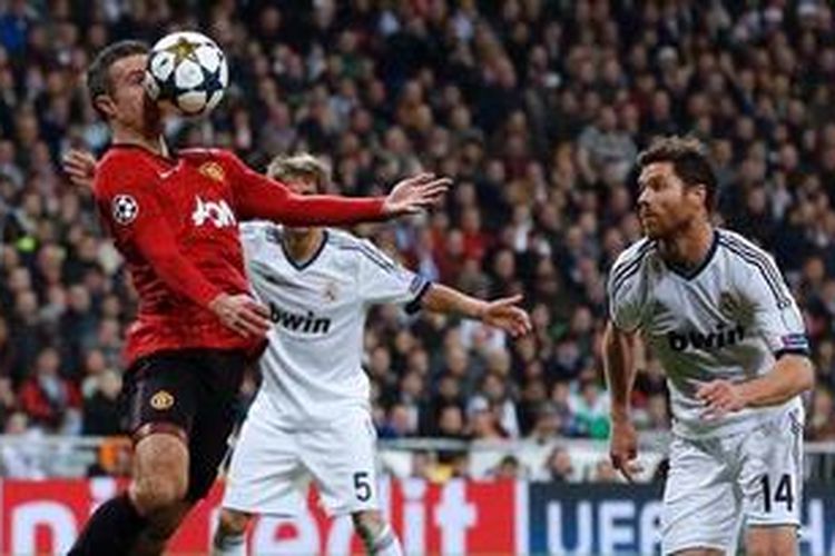 Gelandang Real Madrid, Xabi Alonso (kanan), berusaha merebut bola dari penyerang Manchester United, Robin van Persie, pada leg pertama 16 besar Liga Champions, di Santiago Bernabeu, Rabu 913/2/2013).