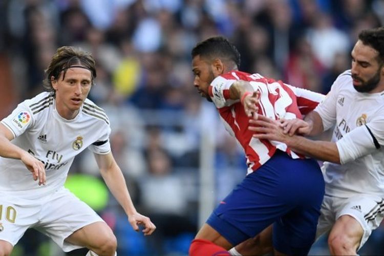 Dua pemain Real Madrid, Luka Modric dan Dani Carvajal, berebut bola dengan bek Atletico Madrid, Renan Lodi, pada pertandingan pekan ke-22 Liga Spanyol di Stadion Santiago Bernabeu, Sabtu (1/2/2020).