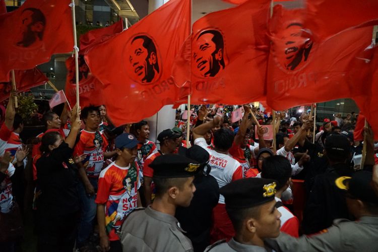 Kelompok relawan Projo turut memberikan dukungan kepada pasangan capres-cawapres nomor urut 01 Joko Widodo-Ma'ruf Amin saat debat pertama Pilpres di Hotel Bidakara, Jakarta Selatan, Kamis (17/1/2019) malam.  Mereka memadati bahu jalan yang menuju lobbby Hotel Bidakara. Ratusan pendukung itu membawa bendera berwarna merah dan bergambar wajah Jokowi.