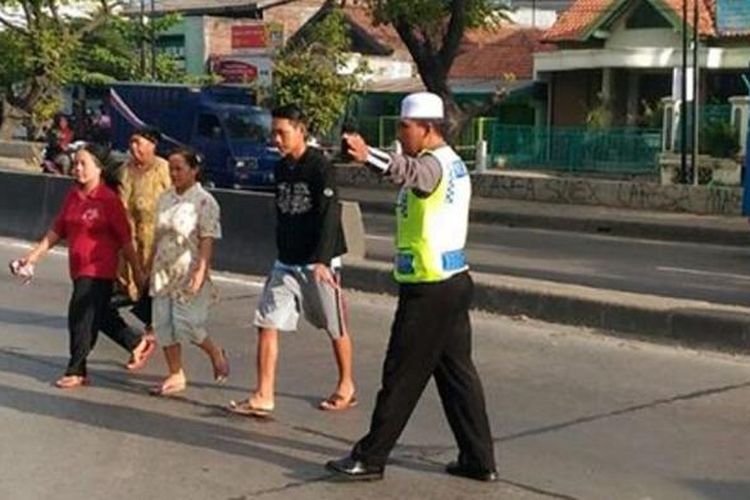 Seorang  santri anggota Satlantas Polres Demak, saat membantu warga menyeberang jalan, Jumat (10/6/2016)