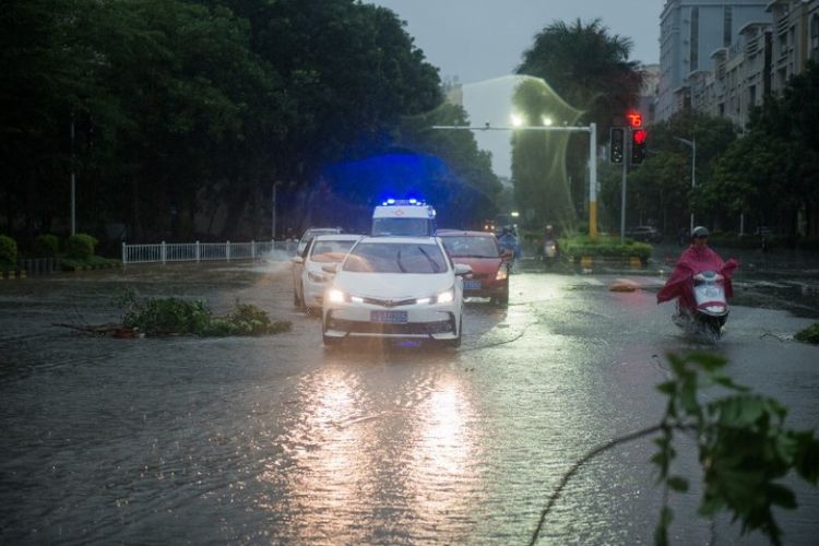 Mobil melewati jalan-jalan terendam banjir akibat siklon tropis Mangkhut di Yangjiang, di provinsi Guangdong, China. Foto ini diambil pada Senin (17/9/2018). (AFP/Nicolas Asfouri)