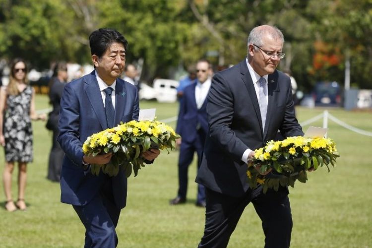 Perdana Menteri Jepang Shinzo Abe (kiri) dan Perdana Menteri Australia Scott Morrison (kanan) meletakkan karangan bunga di Cenotaph War Memorial selama kunjungan dua hari ke Darwin pada Jumat (16/11/2018). (AFP/POOL/Glenn Campbell)