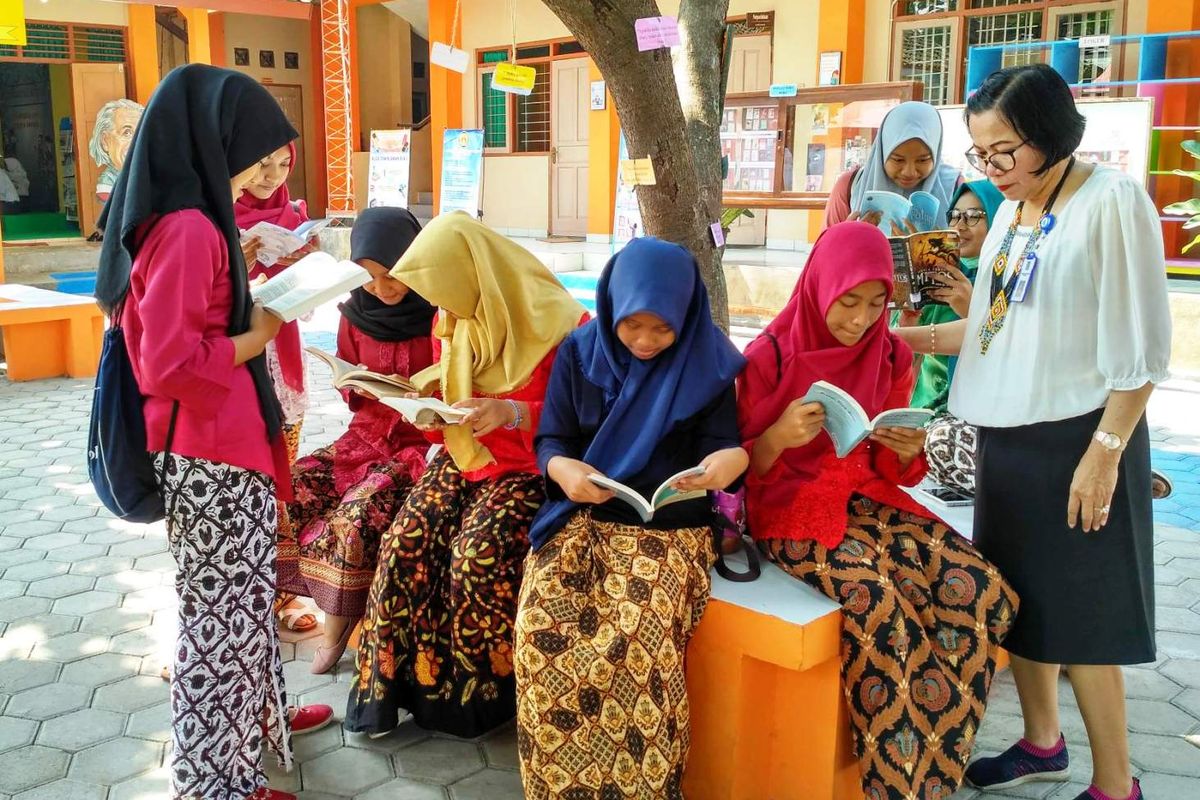 Siswa SMP belajar di taman sekolah.