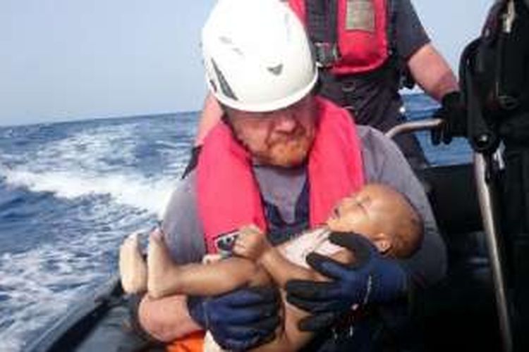 Anggota tim penyelamat  Sea-Watch, Jerman, menggendong bayi yang tewas tenggelam di Laut Mediterania di lepas pantai Lybia, 27 Mei 2016.