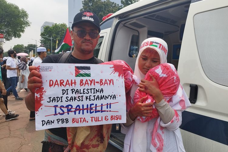 Zubair (26) dan Nia (24) melakukan 'cosplay' sebagai pasutri yang kehilangan anak saat aksi damai bela Palestina di kawasan Monas, Jakarta Pusat, Minggu (5/11/2023). (KOMPAS.com/XENA OLIVIA)