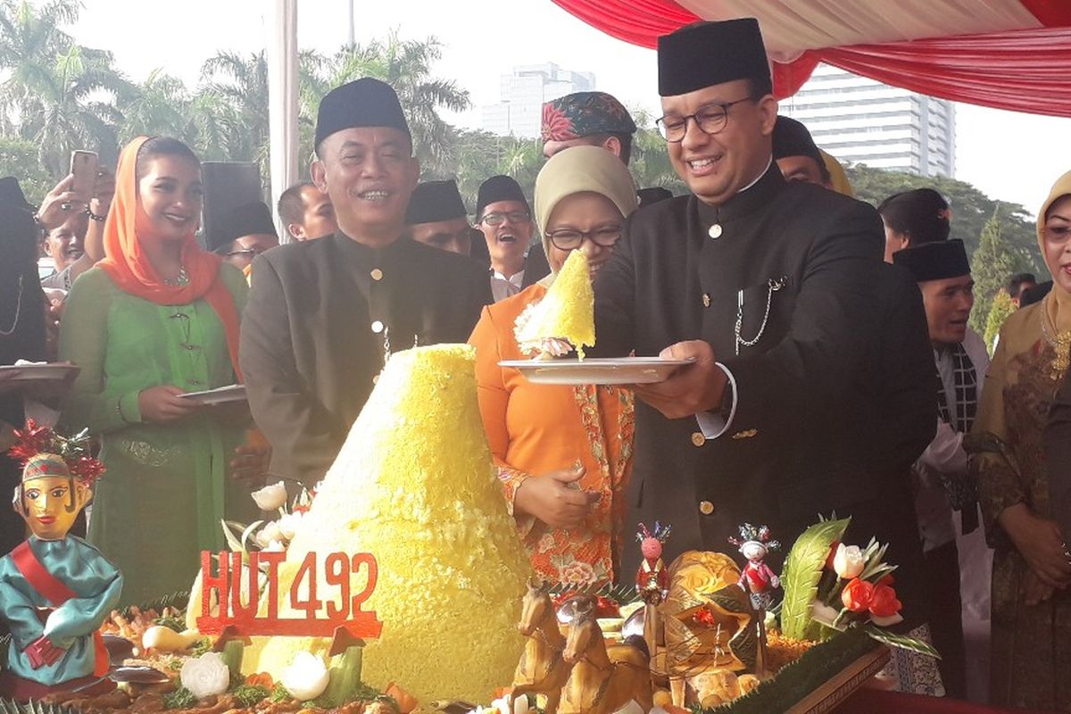 Gubernur DKI Jakarta Anies Baswedan memotong tumpeng selepas upacara HUT ke-492 Jakarta di Monas, Sabtu (22/6/2019).
